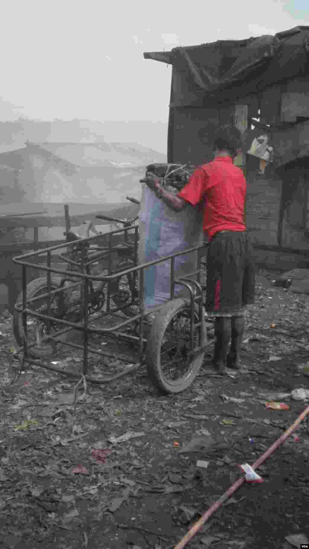A coal worker gets ready to haul away freshly made coal, which sells for a little more than $10 a bag, Smokey Mountain dump site, Manila Bay, Philippines, Dec. 12, 2013. (Simone Orendain for VOA) 