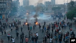 Anti-government protesters set fires and block roads while security forces fire tear gas during a protest in Baghdad, Iraq, Oct. 2, 2019. 