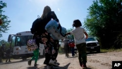Sebuah keluarga migran asal Venezuela bergerak untuk menaiki kendaraan patroli perbatasan setelah mereka dan sejumlah migran lainnya menyeberang perbatasan AS-Meksiko dan menyerahkan diri kepada pihak berwenang di Del Rio, Texas, pada 16 Juni 2021. (Foto: AP/Eric Gay)