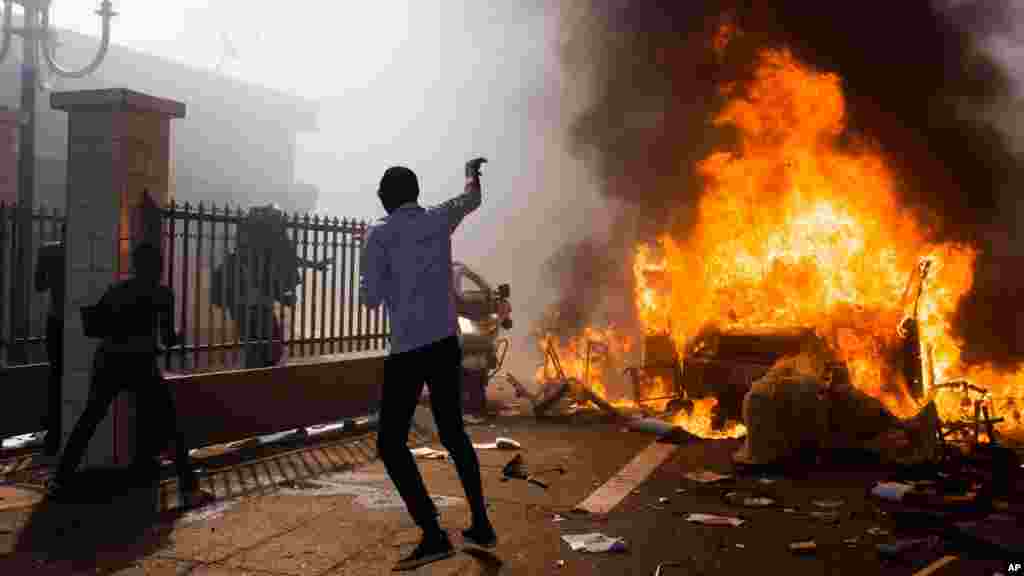 Un véhicule brule devant le parlement que des manifestants ont pris d’assaut, évacuant les députés réunis pour modifier la Constitution en vue permettre un troisième mandat du Blaise Compaoré, Ouagadougou, 30 octobre 2014. (AP Photo/Theo Renaut).