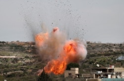 An explosion is seen following Russian airstrikes on the village of al-Bara in the southern part of Syria's northwestern Idlib province.