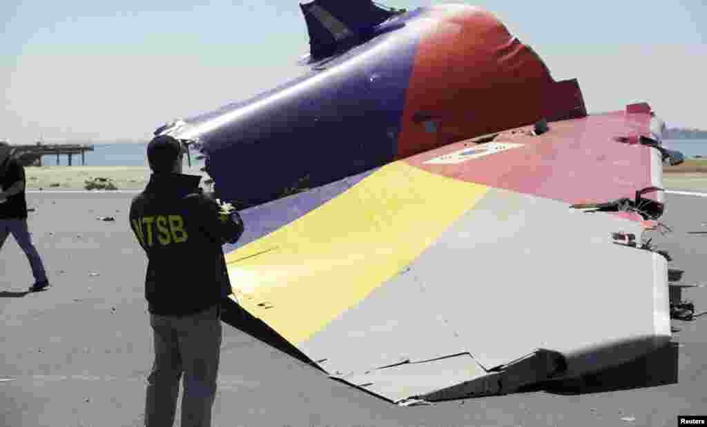Seorang penyelidik dari Badan Keselamatan Transportasi Nasional mengamati bagian ekor pesawat Asiana Airlines penerbangan 214 yang jatuh di bandar udara internasional San Francisco (7/7). (NTSB)