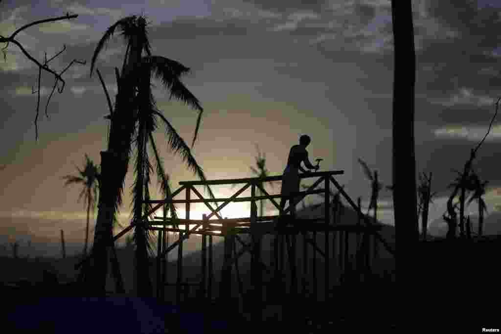 Siluet seorang pria yang membangun kembali rumahnya di kota Palo, Filipina setelah bencana badai topan Haiyan.