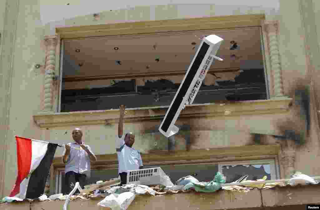 A looter gestures as part of an air-conditioning is thrown down from the Muslim Brotherhood's headquarters after it was burned down by protesters opposing Egyptian President Mohamed Mursi in Cairo's Moqattam district, July 1, 2013.