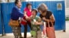 Bao Lanfang, second from right, whose daughter-in-law, son and granddaughter were aboard Malaysia Airlines Flight 370, kneels in grief while speaking to journalists outside the company's offices in Beijing, Aug. 6, 2015. 