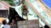 Children around a makeshift shelter beside a message on a board, next to a Christmas tree on a street in Basay, Samar province, Nov. 28, 2013.