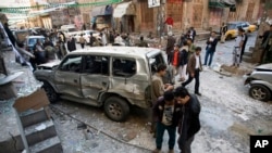 Shiite Houthi men stand near a car damaged by a bomb explosion outside their house in Sanaa Yemen, Tuesday, Dec. 23, 2014.
