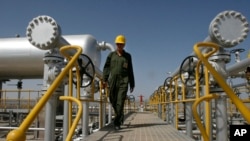 FILE - Oil technician Majid Afshari makes his way to the oil separator facilities in Iran's Azadegan oil field southwest of Tehran.