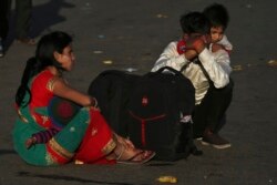 A migrant worker carries a child on his shoulders as his family waits for transportation to their village in New Delhi, India, March 28, 2020.