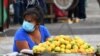 Archivo - Una mujer usa una máscara facial mientras espera clientes en un mercado en Tegucigalpa.
