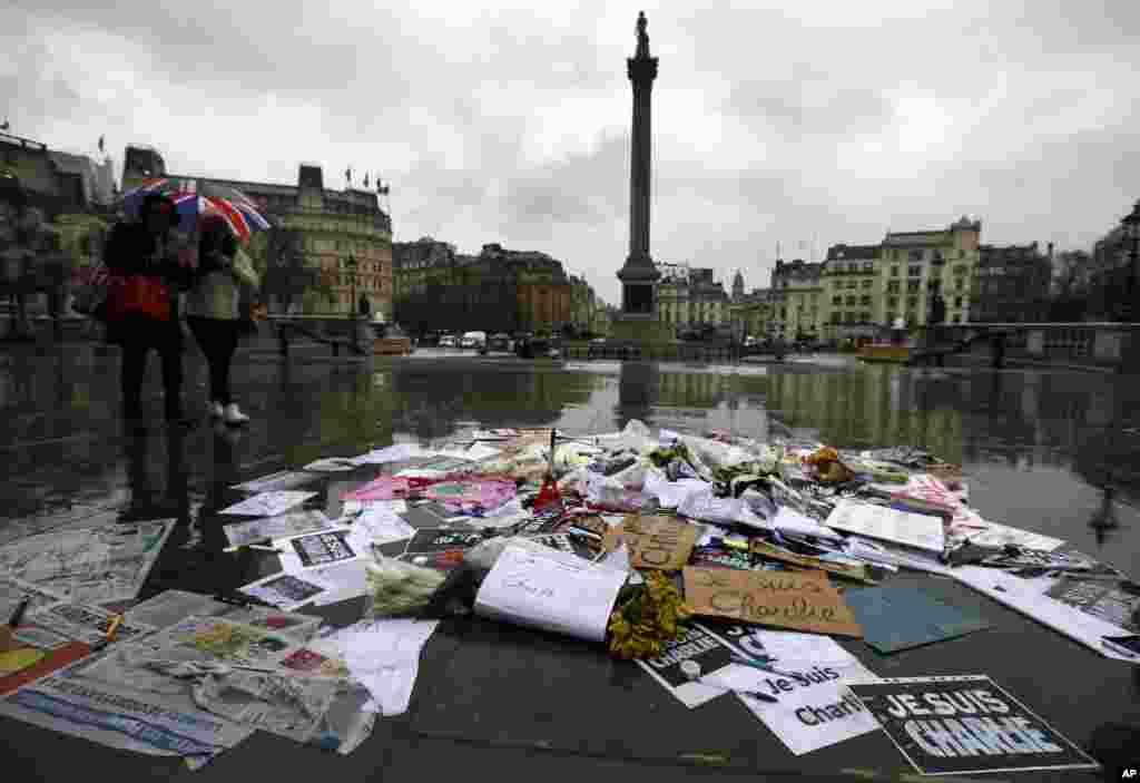 Flowers and pens and placards lie after being placed to show solidarity with those killed in an attack at the Paris offices of weekly newspaper Charlie Hebdo, in Trafalgar Square, London, Jan. 8, 2015.