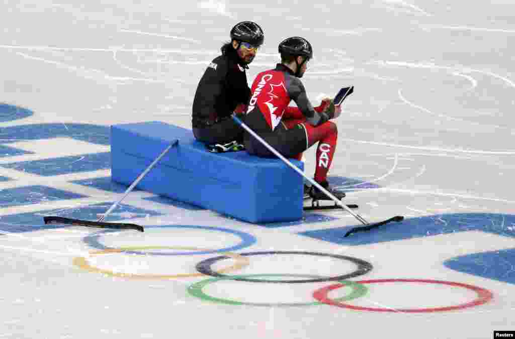 Atlit skate kecepatan trek pendek sekaligus kakak beradik Charles dan Francois Hamelin menonton rekaman latihan mereka di iPad di Iceberg Skating Palace, 4 Februari 2014.