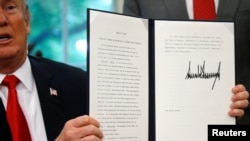 El presidente Donald Trump muestra una orden ejecutiva sobre la política de inmigración después de firmarla en la Oficina Oval en la Casa Blanca en Washington, junio 20, 2018.