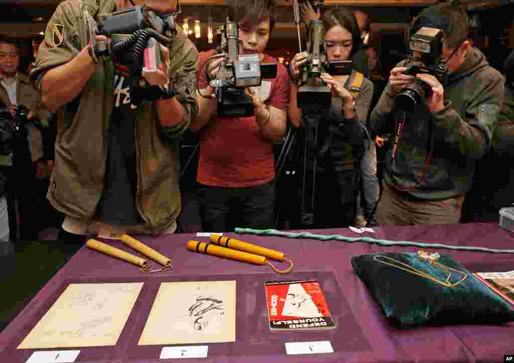 The late action film actor Bruce Lee’s most iconic martial arts weapons, including a pair of yellow lacquered wooden nunchaku, second from left, are displayed during an auction preview in Hong Kong.