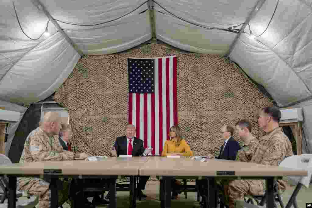 El presidente Donald Trump, acompañado por el asesor de seguridad nacional John Bolton, tercero de la izquierda, la primera dama Melania Trump, cuarta de la derecha, el embajador de Estados Unidos en Irak, Doug Silliman, tercero de la derecha, y líder militar de alto rango.