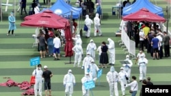 Petugas medis mengatur orang-orang untuk persiapan tes virus corona di sebuah gelanggang olahraga menyusul munculnya kasus-kasus baru Covid-19 di Beijing, China, 15 Juni 2020.