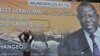 A girl stands next to a campaign poster of Cisse Ibrahima "Bacongo," a candidate for the municipal elections, on April 19, 2013 in Abidjan, two days ahead of the vote. 