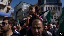 Palestinska djevojčica sa plastičnom puškom na očevima ramenima tokom protesta u Ramali na Zapadnoj obali (Foto: AP/Nasser Nasser)