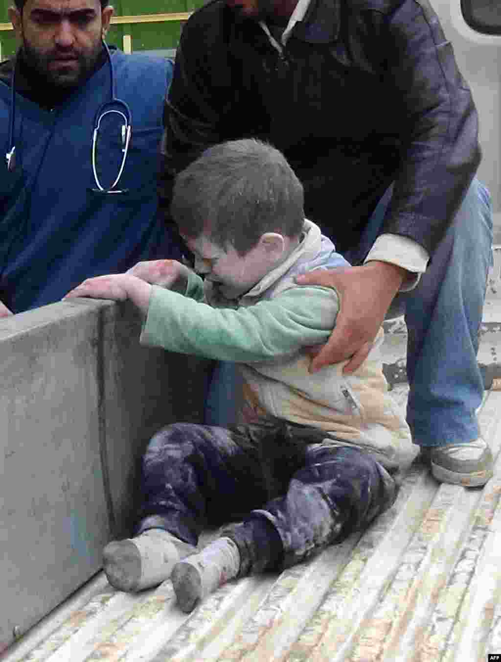Warga Suriah menolong seorang anak kecil yang terluka akibat serangan udara pasukan Suriah di kota Aleppo.