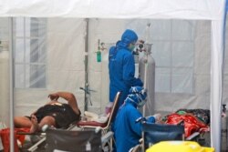 Petugas medis merawat pasien di dalam tenda darurat yang didirikan untuk menampung lonjakan kasus COVID-19, di Rumah Sakit Umum Dr. Sardjito, Yogyakarta, 4 Juli 2021. (AP)