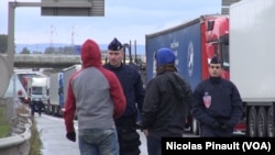 Des policiers discutent avec deux migrants près de la jungle de Calais, France, 14 octobre 2015. (Nicolas Pinault/VOA)