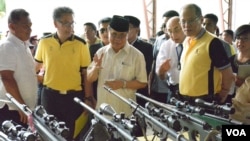 Ketua Front Pembebasan Islam Moro (MILF) Al Haj Murad Ebrahim (tengah) menunjukkan kepada Presiden Filipina Benigno Aquino (kanan) senjata-senjata yang digunakan para pemberontak dalam proses pembicaraan damai di Sultan Kudarat, provinsi Maguindanao, FIlipina, 16 Juni 2015 (Foto: dok).