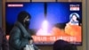 A woman walks past a television screen showing a news broadcast with file footage of a North Korean missile test, at a railway station in Seoul on Jan. 17, 2022.
