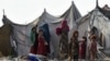 FILE - Children of Afghan refugees play outside tents in Afghan Basti area on the outskirts of Lahore on June 19, 2021 on the eve of World Refugee Day.
