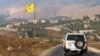 Mobil Penjaga Perdamaian PBB melintas di depan bendera Hizbullah di desa Khiam, perbatasan Lebanon dan Israel, 28 Juli 2020. 