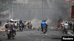 Warga Haiti melewati barikade di sebuah jalan di Port-au-Prince, Haiti, 8 Juli 2018.
