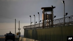 Seorang tentara AS berdiri di atap kendaraannya dengan membawa dengan senapan mesin (kiri), sementara seorang penjaga mengamati sekitarnya dari sebuah menara di penjara Teluk Guantanamo, Kuba (Foto: dok).