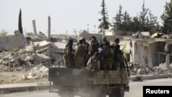 Des rebelles passent des bâtiments en ruine à al-Rai, au nord d'Alep, Syrie, le 2 octobre 2016. 