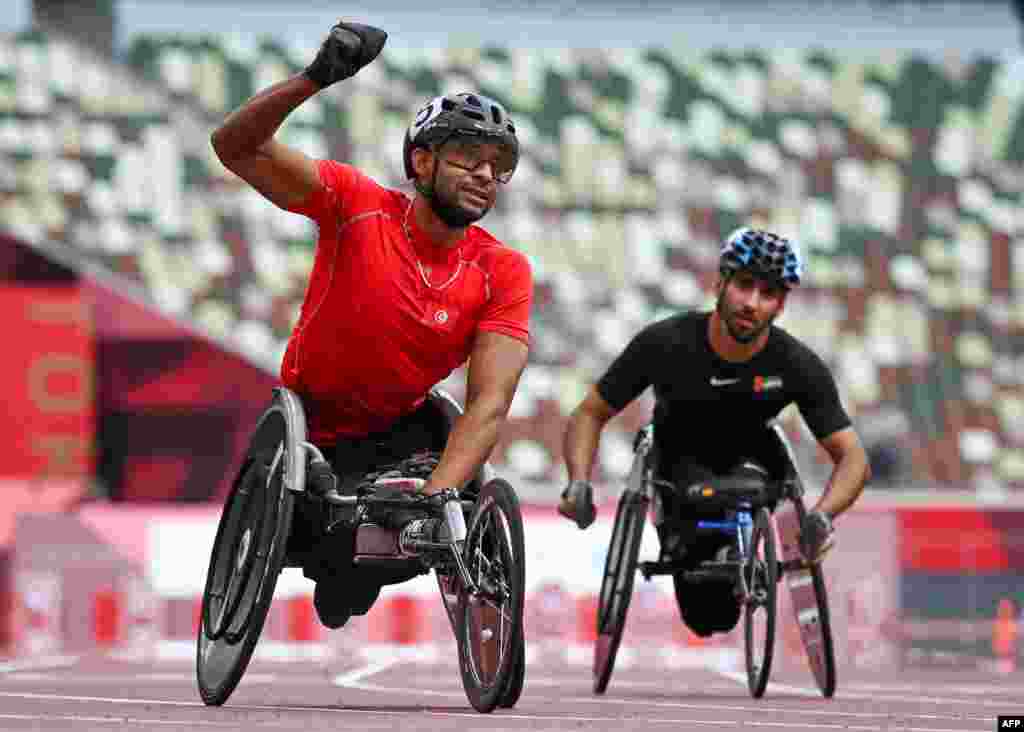 Tunisia's Walid Ktila (L) reacts following his winning race in the men's 100m (T34) final during the Tokyo 2020 Paralympic Games at the National Stadium in Tokyo on August 30, 2021. (Photo by Kazuhiro NOGI / AFP)
