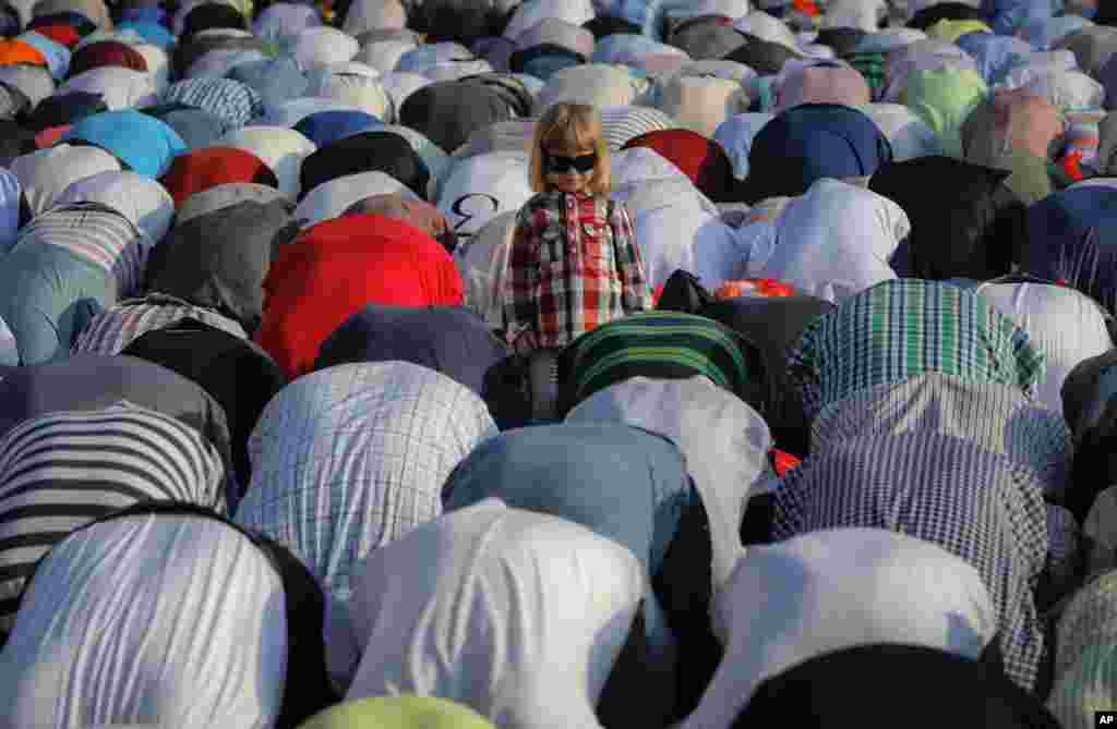 Seorang anak tampak di antara jamaah Muslim yang sedang melakukan shalat Idul Fitri di Bukares, Romania.