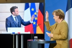 FILE - German Chancellor Angela Merkel waves to French President Emmanuel Macron at the end of a press conference following German-French Security Council video talks in Berlin, Germany, Feb. 5, 2021.