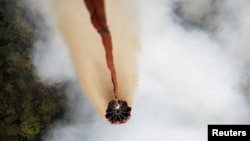 Sebuah pesawat helikopter Mi-17 menyiramkan air di atas hutan yang terbakar di wilayah Ogan Komering Ulu, Sumatra Selatan, 10 September 2015 (Foto: dok). Australia akan mengirim pesawat pemadam kebakaran raksasa dan para penasihat terlatih untuk membantu Indonesia mengatasi kebakaran hutan yang membuat beberapa bagian Asia Tenggara tertutup kabut asap tebal. 