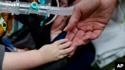 Registered nurse Coleen McMahon, a specialist in pediatric program development, touches the hand of a patient at a pediatric medical facility in Las Vegas, Sept. 10, 2016.