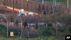 Israeli soldiers work on a military vehicle that was hit by a missile fired by Hezbollah on the Israel-Lebanon border, Wednesday, Jan. 28, 2015.