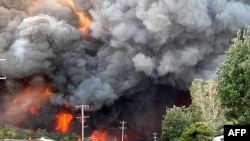 Api dari kebakaran hutan yang tak terkendali terlihat dari daerah perumahan terdekat di Harrington, sekitar 335 kilometer timur laut Sydney, Australia, dalam foto selebaran yang diambil oleh Kelly-ann Oosterbeek. (Foto: AFP)