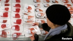 FILE - A customer picks fish fillet as she visits the fish department of a hypermarket of French grocery retailer Auchan in Moscow, January 15, 2015.