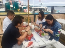 Chinese tourists feast on lobster in Maine. (J.Taboh/VOA)