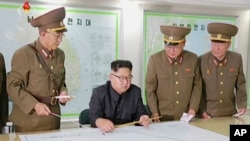 Le leader nord-coréen Kim Jong-Un consulte un plane au milieu des officiers de son armée, Corée du Nord, 15 août 2017.