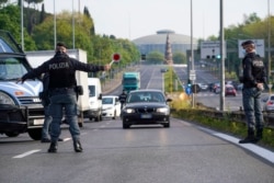 Oficiales de policía detienen automóviles en un punto de control en una calle de Roma el 13 de abril de 2020.