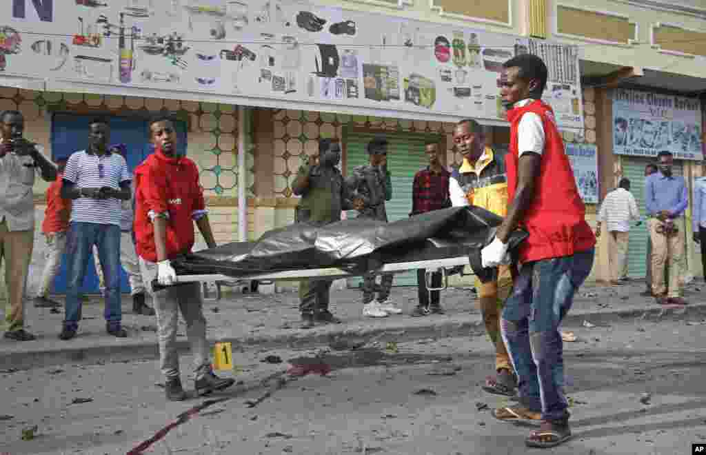 Des travailleurs médicaux enlèvent le corps d'un civil tué dans une explosion d'une voiture piégée près du Parlement, à Mogadiscio, en Somalie, le 25 mars 2018.
