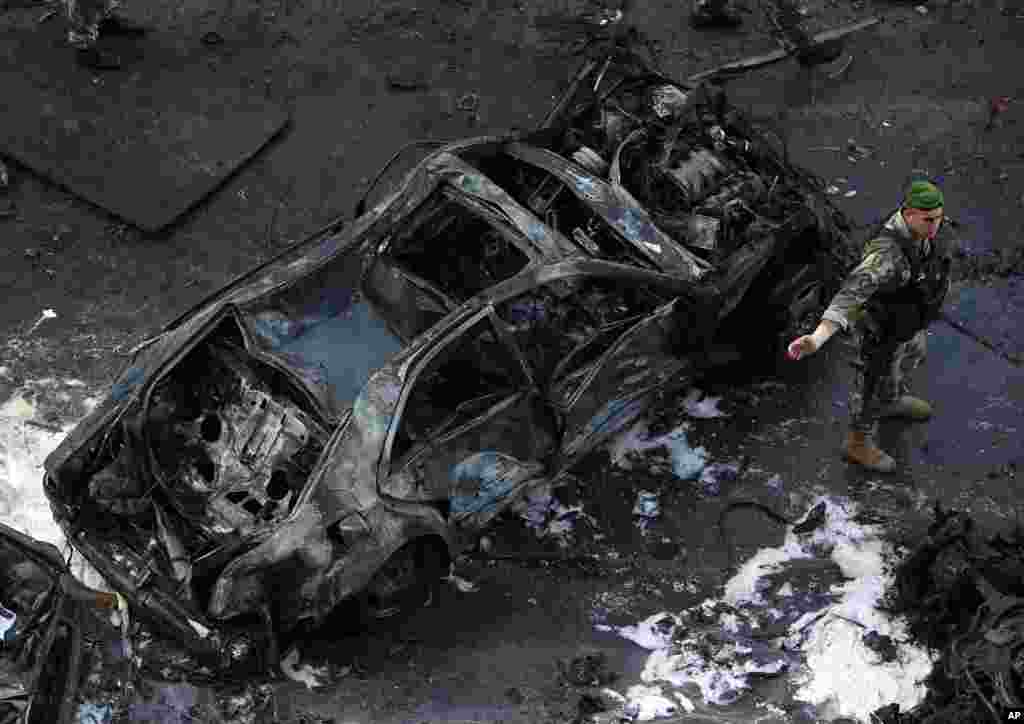 A Lebanese Army soldier stands next to a destroyed car at the scene of an explosion in central Beirut, Lebanon, Dec. 27, 2013.