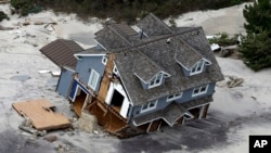 FILE - This Oct. 31, 2012 file aerial photo shows a collapsed house along the Jersey Shore coast. A recent poll shows that a clear majority of mayors are prepared to confront President Donald Trump's administration over climate change.
