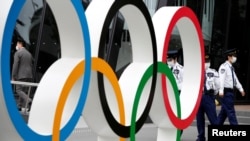 Security personnel stand guard near the Olympic rings monument during a rally by anti-Olympics protesters outside the Japanese Olympic Committee headquarters in Tokyo, Japan, May 18, 2021. 