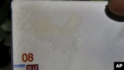 A Chinese man holds up a Chinese passport with details on a page that shows dashes which include the South China Sea as part of the Chinese territory outside a passport office in Beijing, Nov. 23, 2012. 