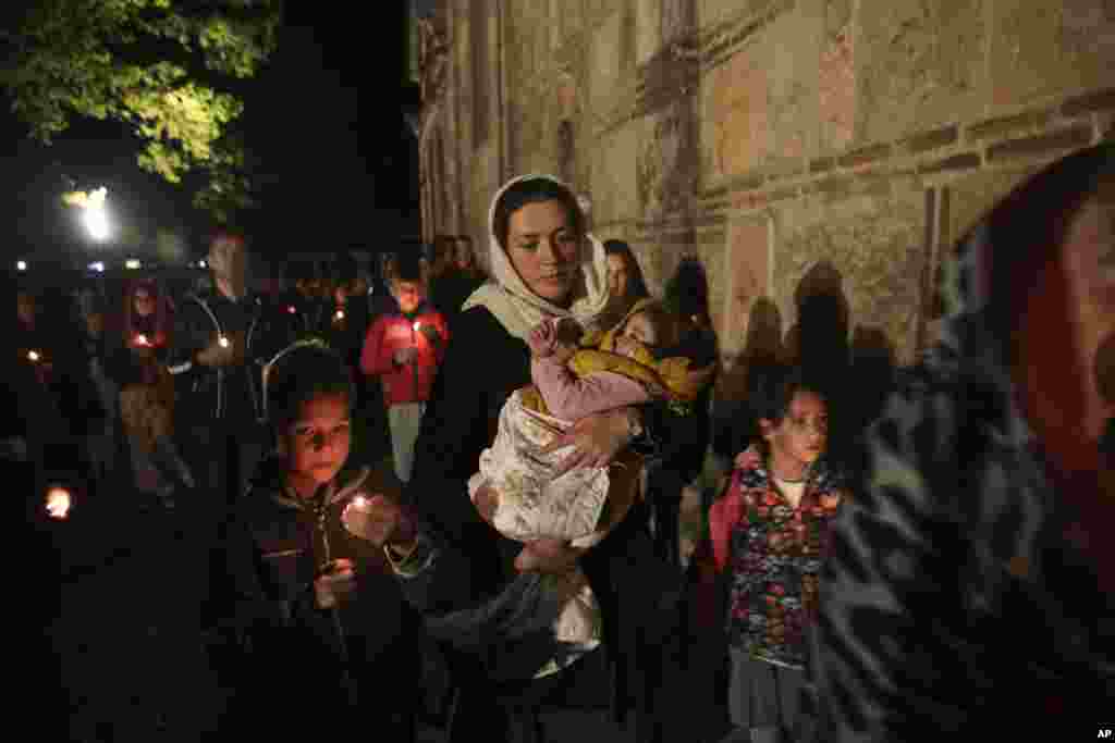 Kosovo Serb Orthodox woman holds her baby during an Easter vigil mass in the monastery of Gracanica during an Easter service, Kosovo, April 16, 2017.