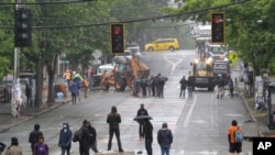 Manifestantes forman barricadas mientras personal del Departamento de Transporte de Seattle remueven otras barricadas en la 10th Ave. y Pine St., en Seattle, Washington, el 30 de junio de 2020.